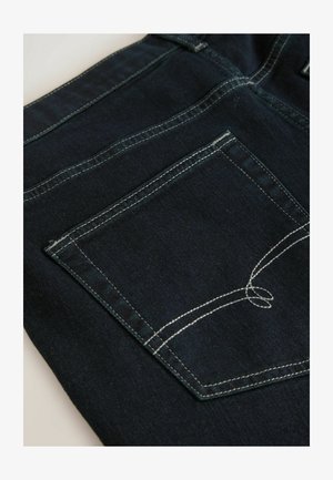 Denim w głębokim niebieskim kolorze z kontrastowym białym przeszyciem. Posiada tylną kieszeń z haftowanym detalem i prostokątnym kształtem.