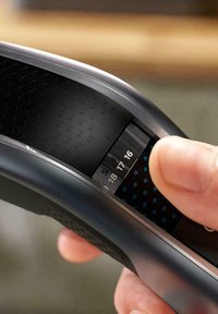 Elektronisch apparaat met een gebogen zwarte behuizing, een gestructureerde grip en een display dat cijfers weergeeft. Een vinger interacteert met de interface.
