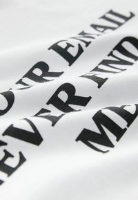 Weißer Stoff mit auffälligem schwarzem Text, der einen kräftigen, grafischen Druck zeigt. Die Textur ist glatt, und das Material wirkt flexibel.