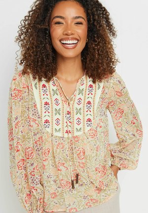 Blumenbluse in Hellgelb mit mehrfarbiger Stickerei. Mit V-Ausschnitt, langen Ärmeln und einer Kordel am Saum. Texturiertes Material.