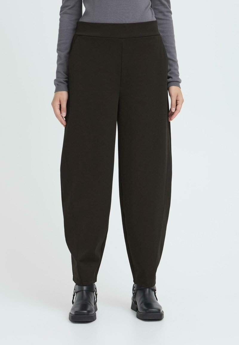 Pantalon noir taille haute à jambes larges, confectionné dans un tissu doux. Il présente une ceinture élastique lisse et se resserre vers la cheville.