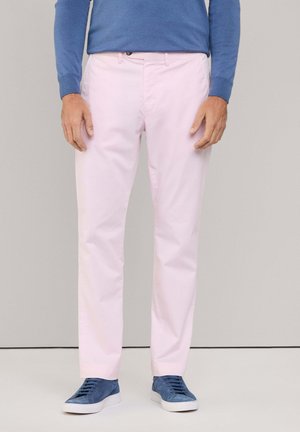 Pantaloni in cotone rosa chiaro con tasche laterali, caratterizzati da un design con frontale piatto, abbinati a sneakers in suede blu e una camicia a maniche lunghe blu.