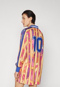 Long-sleeve shirt with vibrant floral design in pink and orange, featuring blue stripes and a large blue number "10" on the back.