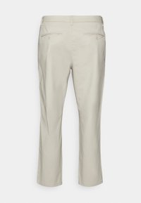 Light beige cotton chinos with a straight leg design, featuring two back pockets with button closures and a smooth texture.