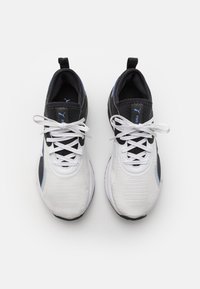 Puma sneakers met een witte en zwarte mesh bovenkant, gestructureerde zijkanten, blauwe accenten en platte veters. Lichtgewicht met een gevoerde zool.