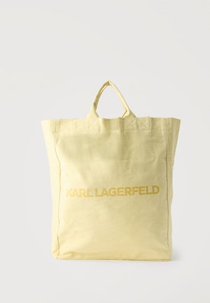 Světlý žlutý látkový nákupní taška s dvěma uchy a názvem značky „KARL LAGERFELD“ vytištěným tučnými písmeny přes přední stranu.