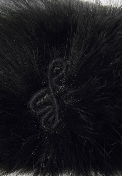 Close-up of a black furry fabric with a black fabric knot button fastener in the center.