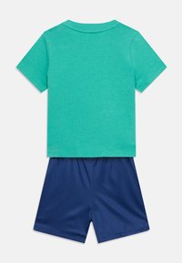 Τιρκουάζ κοντομάνικο t-shirt σε συνδυασμό με σκούρο μπλε αθλητικό σορτς από δίχτυ, απλωμένα επίπεδα σε λευκό φόντο.