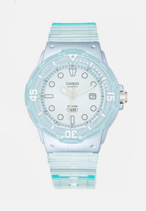 Zegarek kwarcowy Casio z przezroczystą, jasnoniebieską kopertą i paskiem. Posiada okrągłą tarczę, srebrne wskazówki godzinową i minutową oraz okno daty.