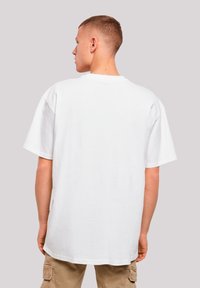 White oversized t-shirt made of cotton, featuring short sleeves, a crew neckline, and a straight hem, worn with beige cargo pants.