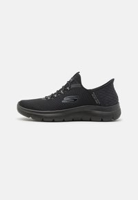 Black athletic shoes with a textured mesh upper, elastic laces, and a cushioned outsole. No visible logos or patterns. Low-profile design.