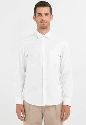 Camicia bianca a maniche lunghe in cotone con chiusura a bottoni e una tasca sul petto. Presenta una vestibilità slim e una texture liscia.