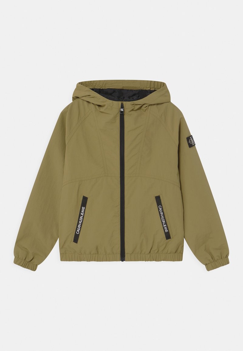 Olivově zelená bunda s kapucí, se zipem vpředu, elastickými manžetami a dvěma černými zipovými kapsami. Na okrajích kapes je logo. Lehký materiál.
