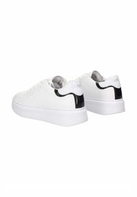 Sneaker bianchi dal design elegante, con un accento nero lucido sul tallone e un retro bianco testurizzato. Suola bianca spessa.
