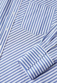Chemise à rayures bleues et blanches avec boutons, montrant une poche avant, des boutons et un poignet à rayures diagonales.