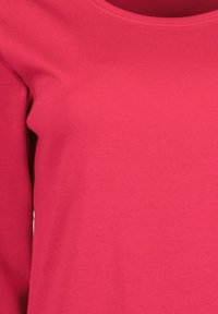 Lyhythihainen puuvillatoppi kirkkaan pinkissä värissä, jossa on pyöreä pääntie ja sileä, tasainen pinta. Ei näkyviä kuvioita tai koristeita.