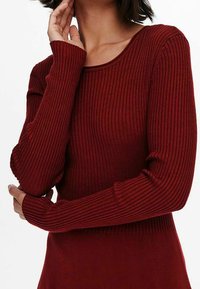 Maglione lungo a maniche lunghe rosso a costine, con un ampio scollo arrotondato e maniche aderenti, realizzato in un morbido materiale a maglia texturizzato.