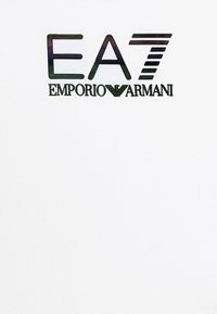 Valkoinen puuvillainen T-paita, jossa on näkyvä musta ja vihreä logo, jossa lukee "EA7 Emporio Armani." Yksinkertainen, pyöreäkauluksinen malli.