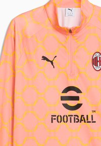 Ružová tréningová bunda na futbal so žltou geometrickou vzorkou, zipsom na krku, čiernym logom Puma a emblémom AC Milána na hrudi.