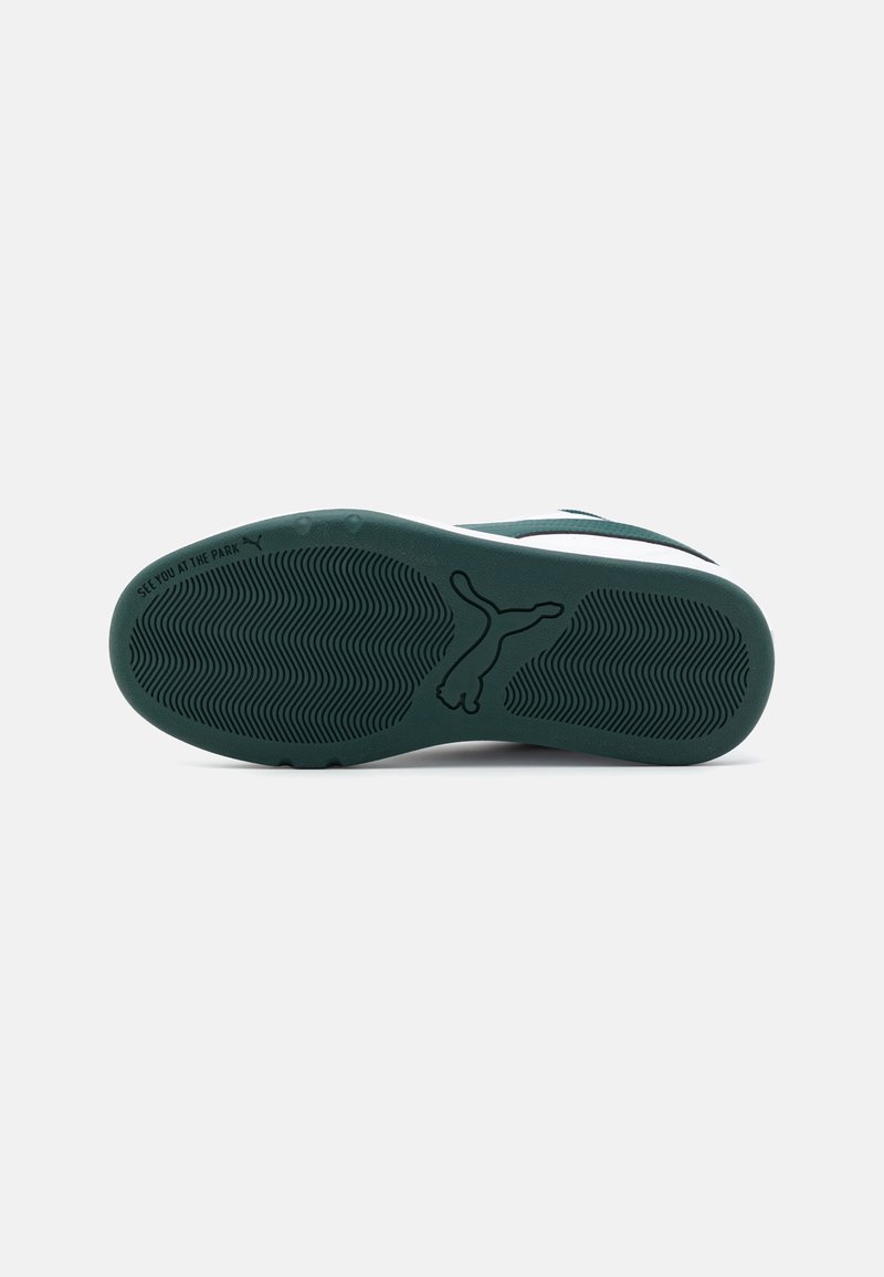 Suela de goma verde con un patrón de banda de rodadura ondulado y un logo de Puma. Presenta una mediasuela blanca y acentos en verde oscuro cerca del talón.