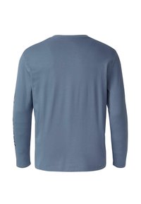 Langslachtige shirt in gedempt blauw, gemaakt van zachte, gladde stof. Heeft een ronde hals en een effen achterkant zonder zichtbare patronen of accenten.