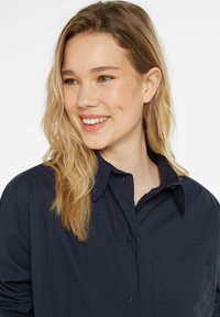 Navy blue button-up shirt with a collared neckline, single chest pocket, and soft fabric. Features long sleeves and smooth texture.
