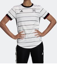 Valkoinen lyhythihainen paita, jossa on mustia raitoja, musta pyöreä kaula-aukko ja punaiset yksityiskohdat hihoissa. Adidas-logo ja Saksan vaakuna esillä.