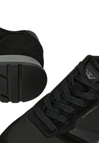 Sneakers neri caratterizzati da una combinazione di materiali in suede e rete, lacci rotondi, suola in gomma testurizzata e un accento del logo sul lato.