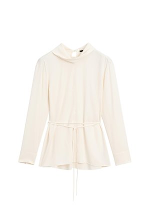 Blouse crème à manches longues avec un col haut et une taille cintrée. Présente un lien à la taille et un tissu lisse et texturé.