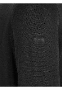 Pullover nero a maglia con un motivo testurizzato, dotato di una piccola etichetta nera sulla manica. Design semplice e aderente con una finitura liscia.