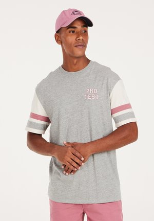 Grijze T-shirt met korte mouwen, voorzien van gestreepte accenten in lichtroze en grijs. Logo "PRO TEST" in het pink op de borst. Lichtroze pet.