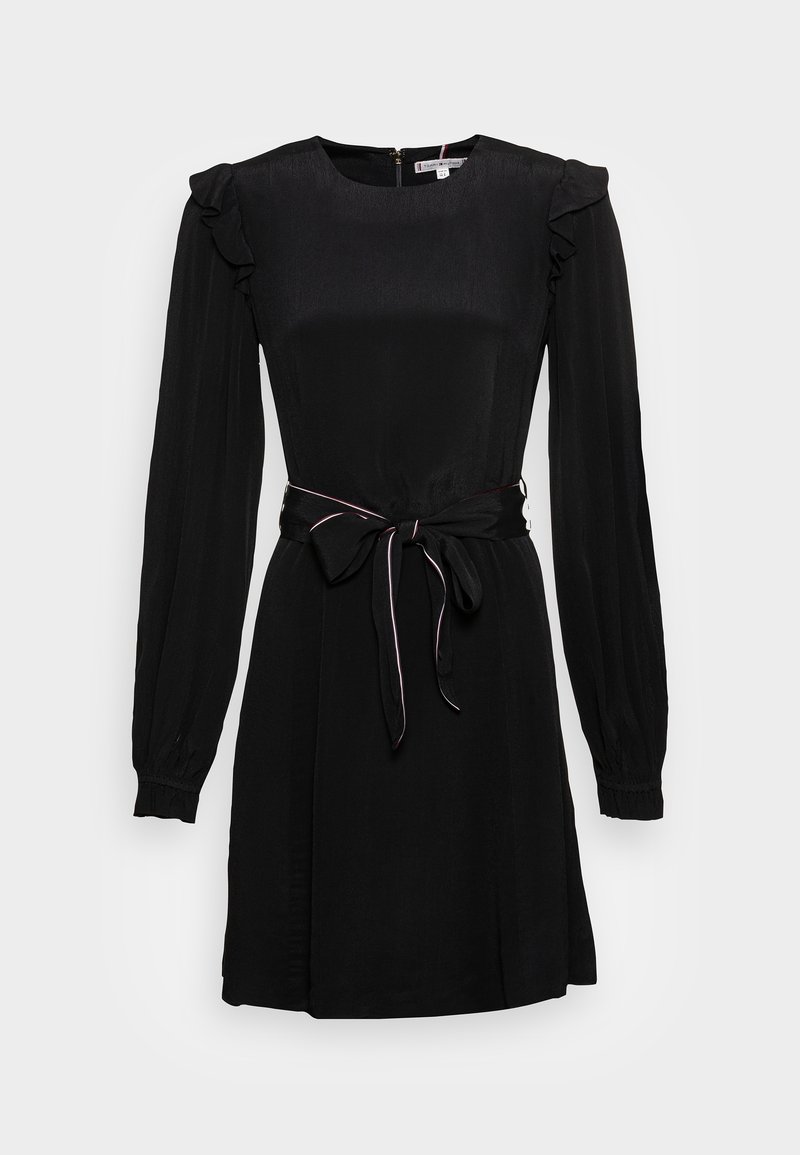 Robe noire à manches longues avec épaules volantées, taille cintrée nouée par une ceinture à nœud, et encolure ronde.