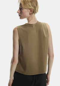 Hnedý bezrukávový top s okrúhlym výstrihom, jemná tkanina a skrátený dizajn. Obsahuje bočné rozparky a jemné švy.