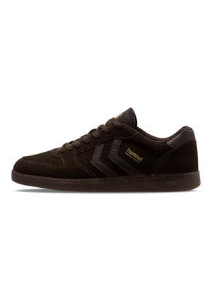 Ciemnobrązowy zamszowy sneaker z pasującymi sznurowadłami, paskami z logo w kształcie szewrona, podeszwą o niskim profilu i oznaczeniem "hummel" z boku i na pięcie.