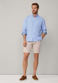 Lyseblå skjorte med knapper og rutete mansjetter, beige shorts og brune slip-on sko. Glatt stoff; avslappet passform. Minimalistisk design.