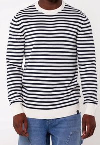 Pull rayé bleu marine et blanc en tissu tricoté doux, avec un col rond et des poignets et un ourlet côtelés. Coupe décontractée.