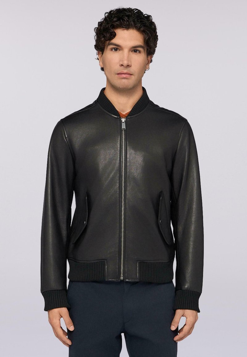 Chaqueta bomber de cuero negro con puños y dobladillo acanalados, cierre de cremallera en la parte delantera y dos bolsillos laterales, con una textura suave y un diseño sencillo.
