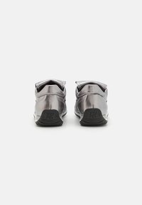 Metallisk grå sneakers med en glatt overflate, avrundet form, polstret krage og svart gummisåle med logo på hælen.