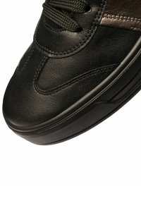 Sneaker in pelle nera con dettagli testurizzati, lacci neri e punta arrotondata liscia, dotata di suola in gomma con motivo per migliorare la trazione.