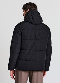 Giacca a vento nera con cappuccio, caratterizzata da un design trapuntato, texture liscia e polsini elasticizzati, vista da dietro.