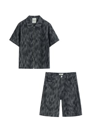 Chemise zippée à manches courtes et short longueur genou avec un motif rayé noir et blanc, tous deux provenant du même ensemble assorti.