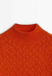 Pull tricoté orange vif avec un col montant côtelé et un motif torsadé texturé sur le corps.