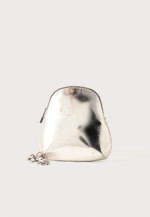 Un petit sac à dos métallique argenté avec une fermeture éclair sur le dessus et une bandoulière chaîne épaisse, présenté sur un fond clair uni.