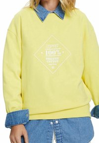 Žlutá mikina z 100% organické bavlny má bílý potisk ve tvaru diamantu. Má denimový límec a manžety, které dodávají vrstvený vzhled.