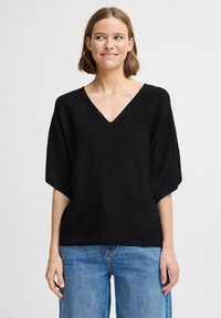 Haut noir à manches courtes avec un col en V et une coupe décontractée. Fabriqué dans un tissu lisse, il présente des manches larges et un ourlet droit.