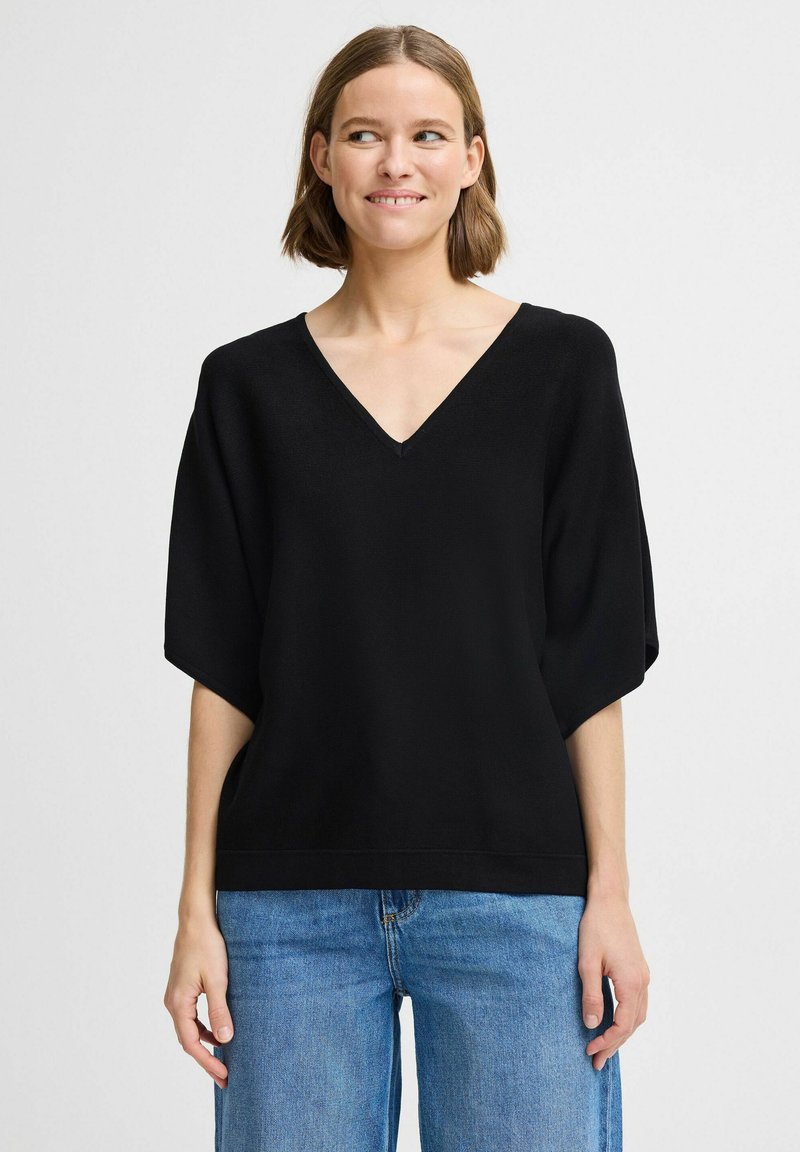Haut noir à manches courtes avec un col en V et une coupe décontractée. Fabriqué dans un tissu lisse, il présente des manches larges et un ourlet droit.