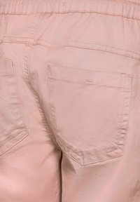 Light pink trousers with a soft, smooth texture. Features two back pockets, elastic waistband, and subtle stitching details.