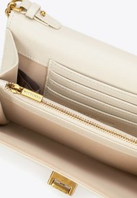 Světle béžová peněženka s texturovaným povrchem, zlatými kovovými doplňky, zipovou kapsou a několika přihrádkami na karty uvnitř. Viditelné logo značky.