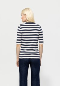 Navy and white striped short-sleeve top with a round neck, made from a textured fabric, paired with dark denim.