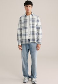 Ruudullinen flanellipaita valkoisena, laivastonsinisenä ja vaaleansinisenä; kauluksellinen malli, jossa etunapit; puettu valkoisen t-paidan päälle ja yhdistetty vaaleisiin farkkuihin.